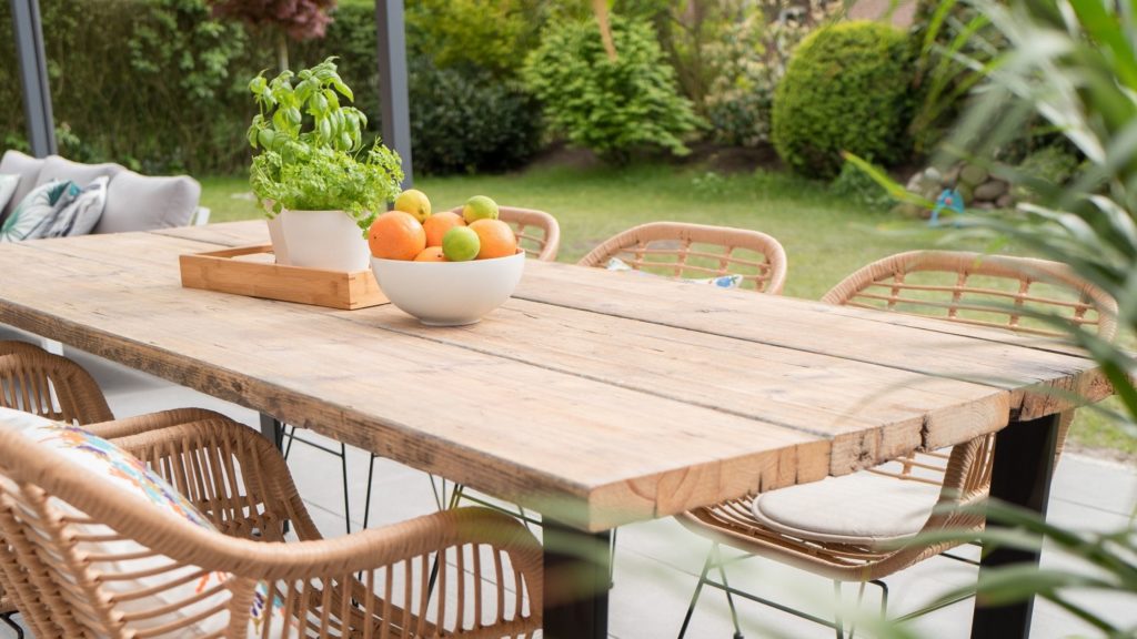 Wooden garden table and chairs with a fruit bowl in the centre.